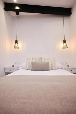 a bedroom with a white bed with two lights at Villa Julia in Ribadavia