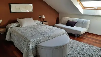 a bedroom with a bed and a chair and a window at Rego de Flores in Viveiro