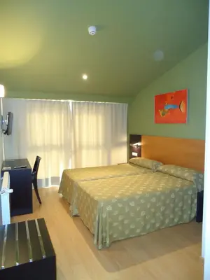 a bedroom with a bed and a table and a window at Hotel Parrilla el Zangano in Boal