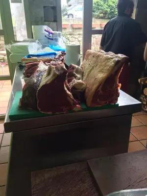 a table with a bunch of meat on a counter at Hotel Parrilla el Zangano in Boal