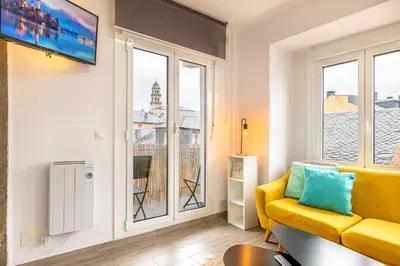 a living room with a yellow couch and a window at Nômada Castillo _ VUT-LE-251 in Ponferrada