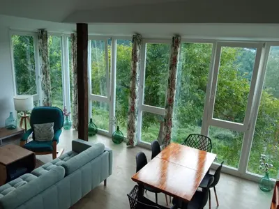 a living room with a couch and a table and windows at O Salgueiral in Castro Caldelas