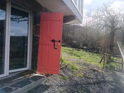 a red door on the side of a house at O Salgueiral in Castro Caldelas