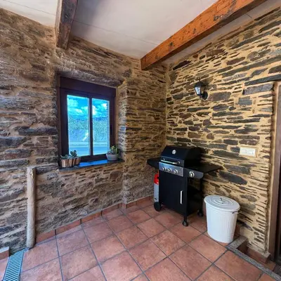 a stone walled kitchen with a stove and a window at A Barreira in Ferrol