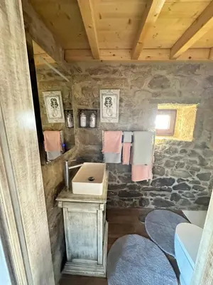 a bathroom with a sink and a stone wall at El nido del cuco in Padrón