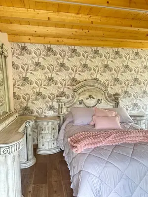 a bedroom with a bed and a wall with wallpaper at El nido del cuco in Padrón