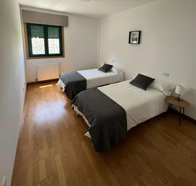 a bedroom with two beds and a wooden floor at PortoHome 1 in Portomarin