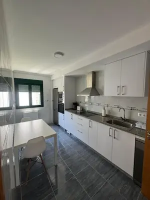 a kitchen with white cabinets and a table and a sink at PortoHome 1 in Portomarin