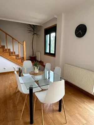 a dining room with a glass table and white chairs at PortoHome 1 in Portomarin