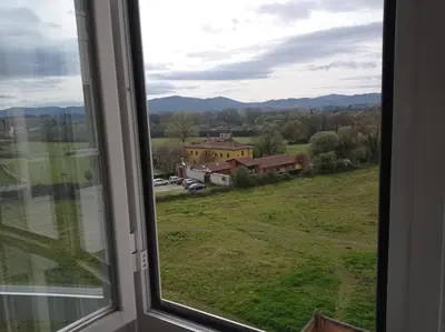 a window with a view of a field and a house at Delta in Monforte de Lemos