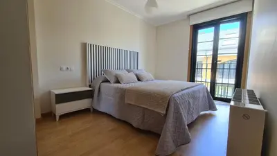 a bedroom with a bed and a large window at Piso Vega Foz in Foz