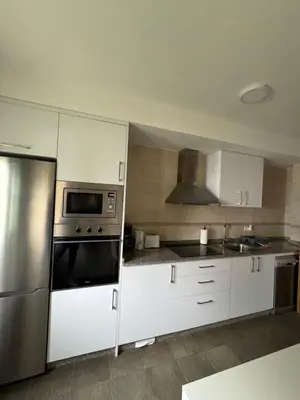 a kitchen with white cabinets and a stainless steel refrigerator at PortoHome 2 in Portomarin
