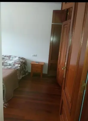 a bedroom with a bed and a wooden door at PISO DEL PARQUE 2 in Santiago de Compostela