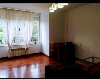 a living room with a table and two windows at PISO DEL PARQUE 2 in Santiago de Compostela