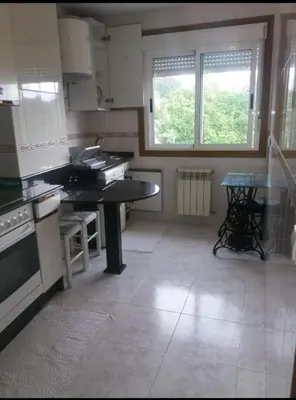 a kitchen with a counter and a table in it at PISO DEL PARQUE 2 in Santiago de Compostela