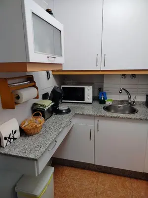 a kitchen with white cabinets and a sink and a microwave at PONFETEMPLE in Ponferrada
