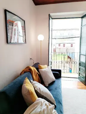 a living room with a blue couch and a large window at Steve Apartamento in Viveiro
