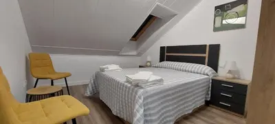a bedroom with a bed and a yellow chair at Temple I in Ponferrada
