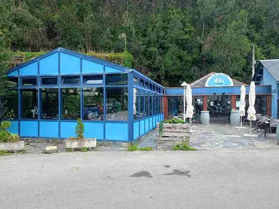 a blue building with umbrellas in front of it at Casa Fernanda Viavélez in El Franco