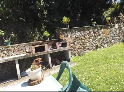 a stone wall with a fireplace in a yard at Casa Fernanda Viavélez in El Franco