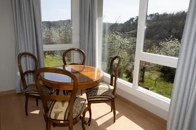 a table and chairs in a room with windows at Casa da Cocha in Chantada
