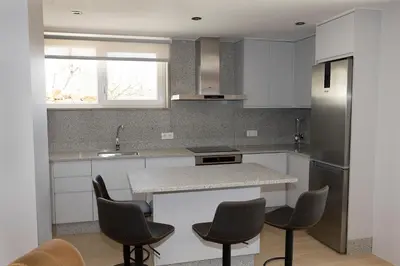 a kitchen with white cabinets and a counter with chairs at Casa da Cocha in Chantada