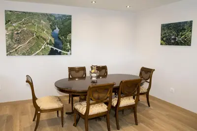 a dining room table with chairs and a painting on the wall at Casa da Cocha in Chantada