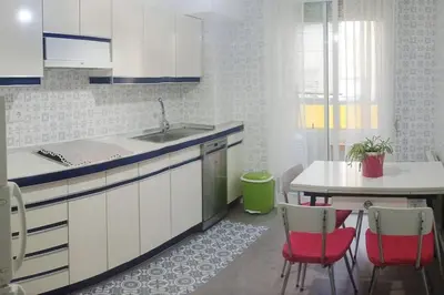 a kitchen with a sink and a table with red chairs at Piso en Ourense- Sempre Maruxiña in Ourense