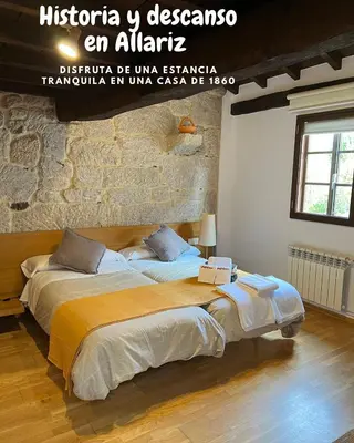 a large bed in a room with a brick wall at Pensión rural Pallabarro in Allariz