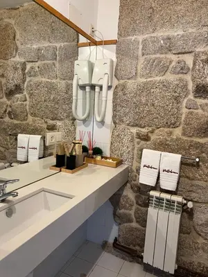 a bathroom with a sink and a stone wall at Pensión rural Pallabarro in Allariz