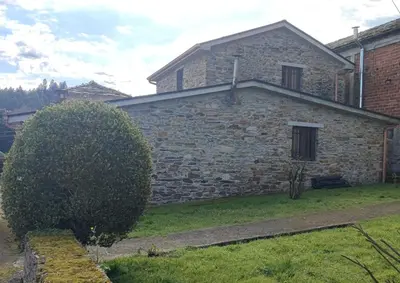 an old stone house with a bush in front of it at CASA GALLARDO in Ribadeo