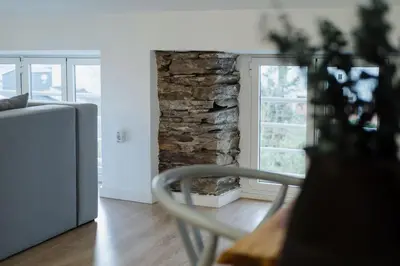 a living room with a couch and a stone wall at Ático Isabel, diseño y calidez junto a la Muralla Romana in Lugo