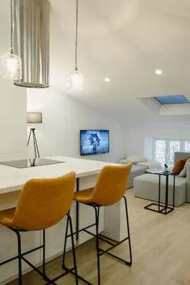 a kitchen and living room with a counter and chairs at Ático Isabel, diseño y calidez junto a la Muralla Romana in Lugo