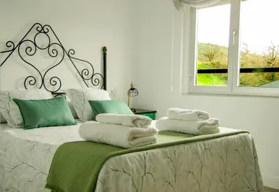 a white bedroom with a bed with towels on it at Apartamento El descanso de Fuco in Molinaseca