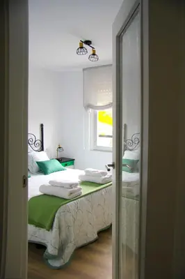 a bedroom with a bed with white sheets and a window at Apartamento El descanso de Fuco in Molinaseca
