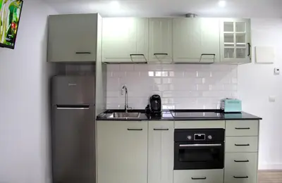 a kitchen with white cabinets and a stainless steel refrigerator at Apartamento El descanso de Fuco in Molinaseca