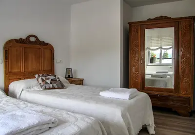 a bedroom with two beds and a wooden dresser at Apartamento El descanso de Fuco in Molinaseca