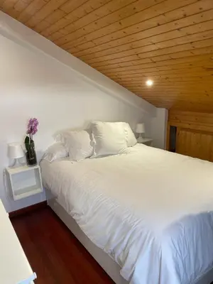 a bedroom with a white bed with a wooden ceiling at La Casita in Nogueira de Ramuin