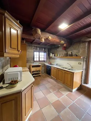 a large kitchen with wooden cabinets and a tile floor at La Casita in Nogueira de Ramuin
