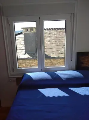 a bedroom with two windows and a bed with blue sheets at A Travesía Dos Soños, Pedreiras in Sarria