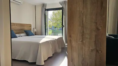 a bedroom with a bed and a large window at Apartamentos O Caneiro in Portomarin