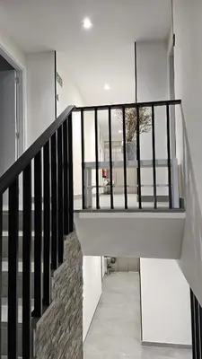 a staircase in a house with black railing at Apartamentos O Caneiro in Portomarin