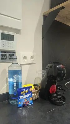 a bottle of water sitting on a counter next to a coffee maker at Apartamentos O Caneiro in Portomarin
