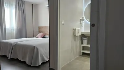 a small bedroom with a bed and a mirror at Apartamentos O Caneiro in Portomarin