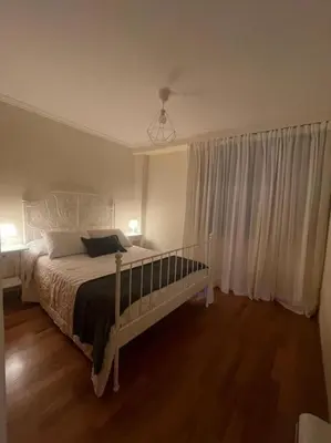 a bedroom with a bed and a window with white curtains at Apartamento con encanto en Cuntis in Cuntis