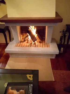 a stone fireplace in a living room with a table at Casa Sanmartín in Maside