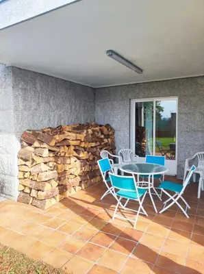 a patio with a table and chairs and a stone wall at Casa Sanmartín in Maside