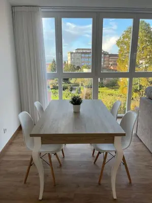 a dining room table with white chairs and a large window at Apartamento céntrico con vistas in Santiago de Compostela