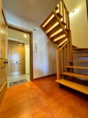 a hallway with a wooden staircase and a door at Orbayu apartamento Foz in Foz