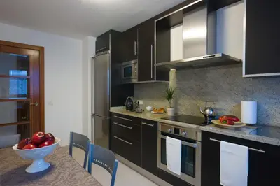 a kitchen with black cabinets and a bowl of fruit on a table at Alojamiento Santa Maria in Milladoiro